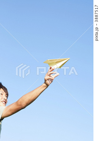 紙飛行機 飛ばす 手元 青空の写真素材