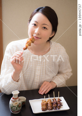 日本酒 食べる 女性 焼き鳥の写真素材