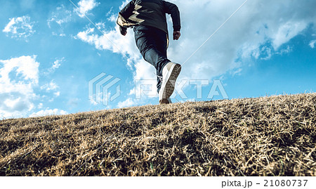 男性 丘 後ろ姿 走るの写真素材