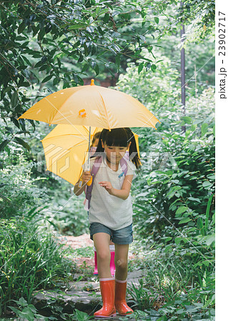女の子 ジャンプ傘 雨降り 長靴の写真素材