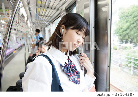 寄りかかる 電車 寝る 疲れの写真素材