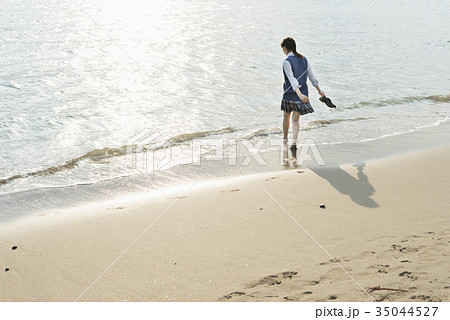 海 夕焼け 女の子 波打ち際の写真素材