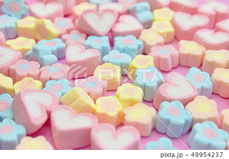 White and pink heart-shaped marshmallows are scattered from a cup