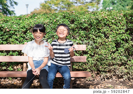 女の子 男の子 座る ベンチの写真素材