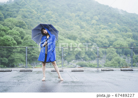 雨の中でレインコートを着た女性の写真素材
