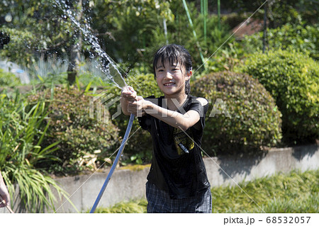 子供 水 水遊び ホースの写真素材