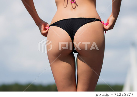 Lets go for a dip. Shot of a young woman taking her bikini top off