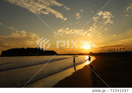 海 夕焼け 女の子 波打ち際の写真素材