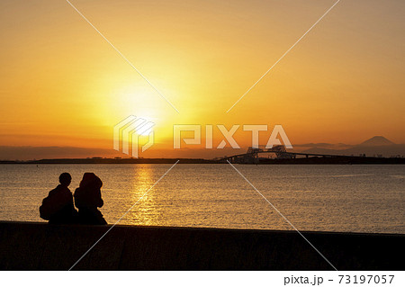 男女 カップル 夕日 シルエットの写真素材