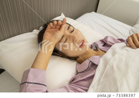 病気で寝込んでいる女性/体調の悪い女性/ベットに寝ている美しい女性