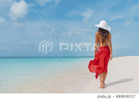 Woman walking on beach in blue fashion beachwear bathing suit and sarong  pareo sun skirt relaxing in luxury Caribbean vacation holidays. Summer or  winter getaway destination. Stock Photo