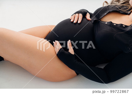 A Pregnant Woman Topless In Pajama Pants In Profile In A Home