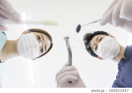 歯科治療イメージ　患者を覗き込む歯科医と歯科衛生士